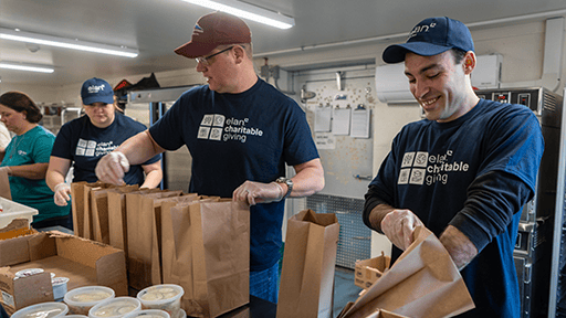 Four volunteers pack food into bags.