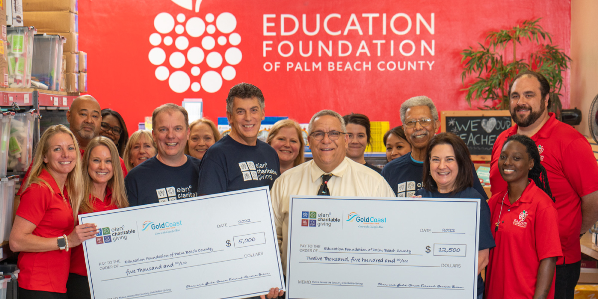 Group of volunteers holding two large donation checks