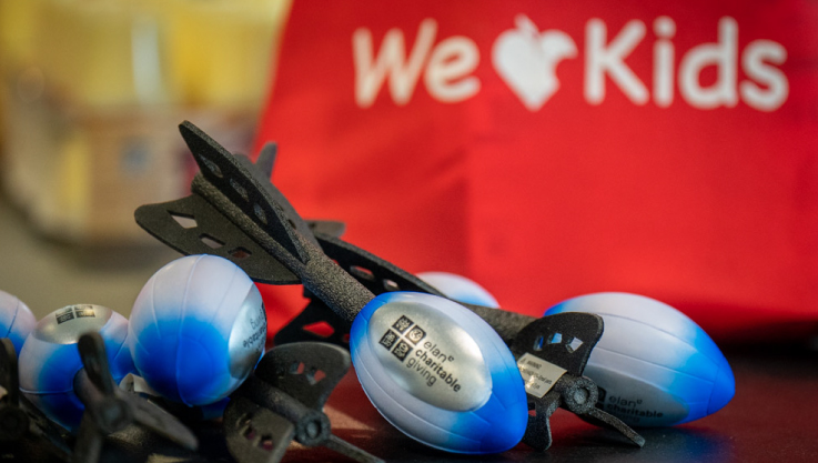 A pile of blue and silver Nerf rockets lay on a table in front of a red bag. 