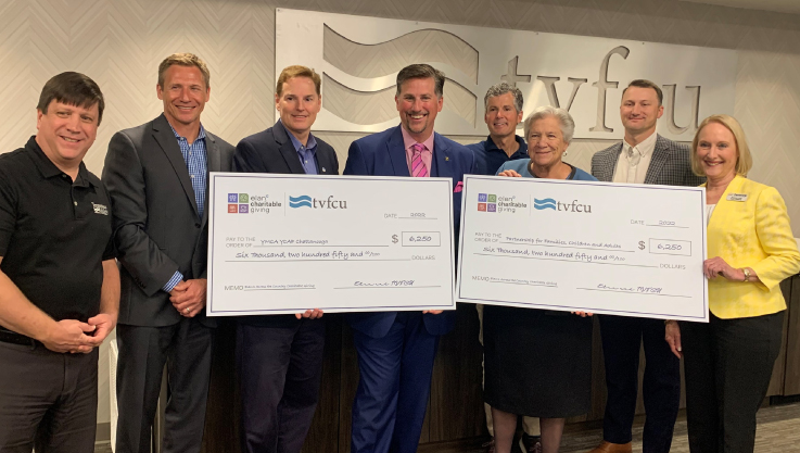 A group of individuals stand together holding a large promotional check. 